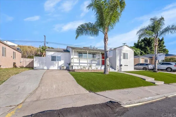 a front view of a house with a garden and palm trees