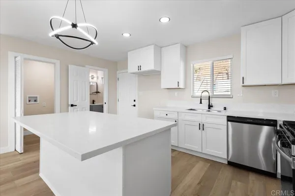 a kitchen with stainless steel appliances a sink a stove a refrigerator and white cabinets