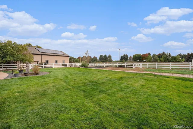 a view of a big house with a big yard and large trees