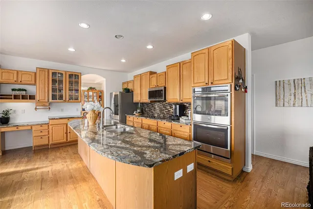 a kitchen with stainless steel appliances granite countertop a refrigerator a stove and a sink