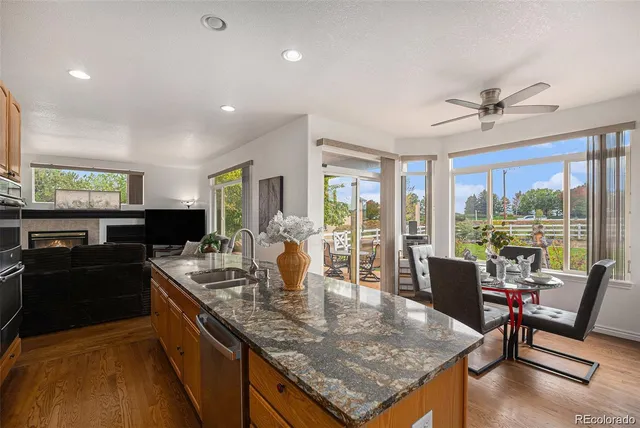 a dining hall with stainless steel appliances granite countertop a stove top oven a dining table and chairs with wooden floor