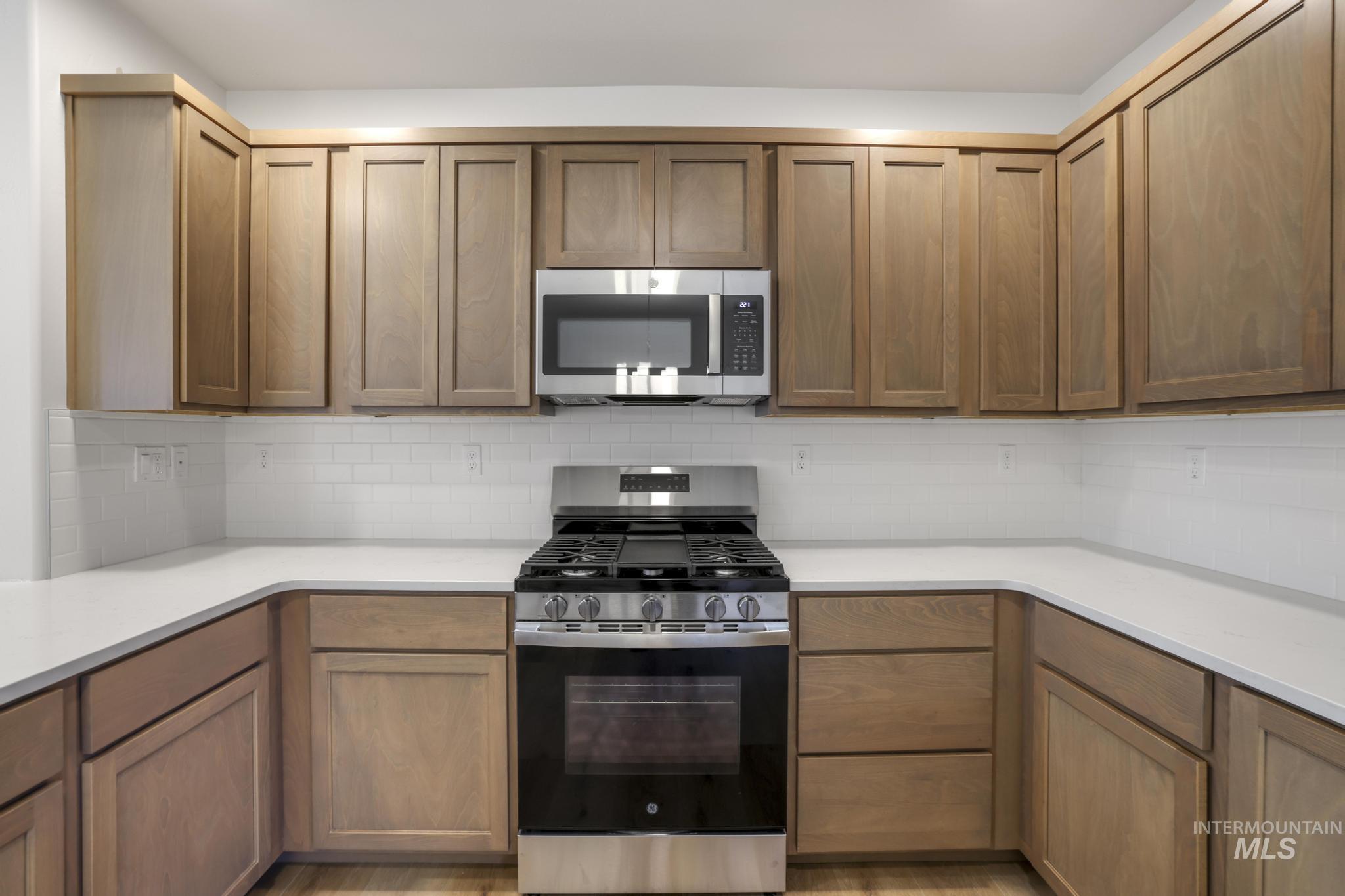 1542 Kenyon Road Twin Falls, ID 83301 - Photo 13 of 26 Kitchen featuring appliances with stainless steel finishes, decorative backsplash, and brown cabinetry