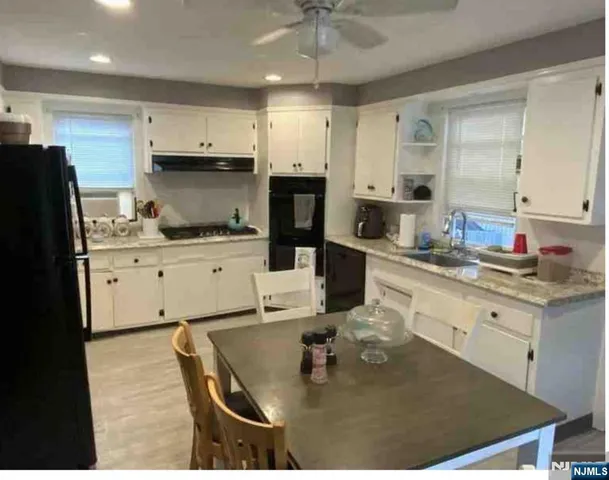 a kitchen with stainless steel appliances granite countertop a sink stove refrigerator and cabinets