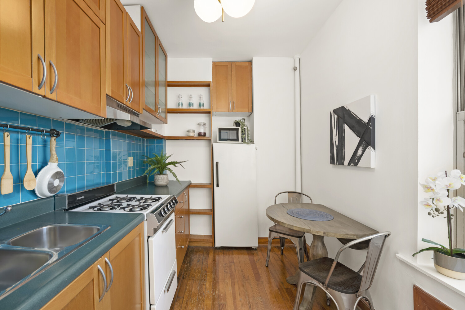 232 East 6th Street, Unit 6E Manhattan, NY 10003 - Photo 4 of 7 a kitchen that has a microwave a stove a sink and a dining table with granite countertop