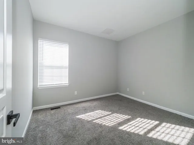 an empty room with chandelier fan and windows