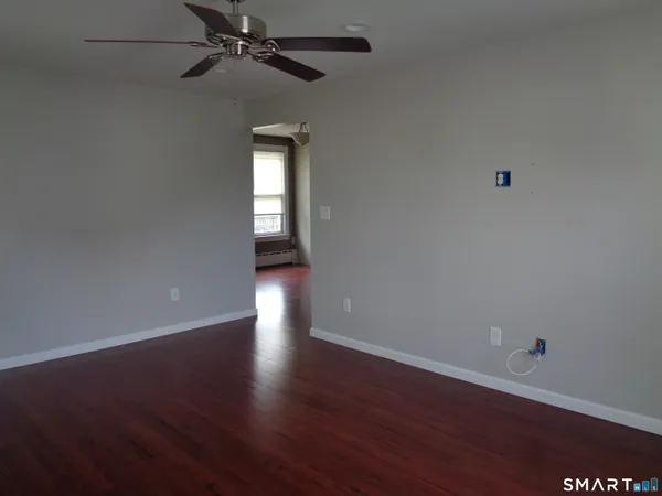 a view of an empty room with wooden floor and a window