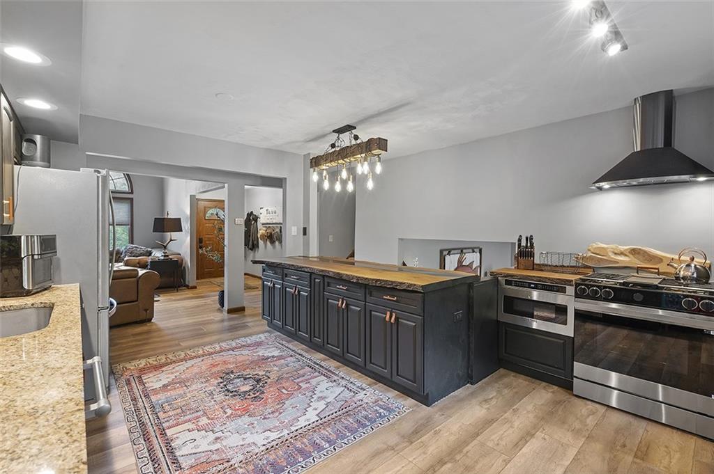6178 Baker School Road Trafford, PA 15085 - Photo 12 of 48 a kitchen with stainless steel appliances granite countertop a stove a sink dishwasher a refrigerator and a fireplace with wooden floor