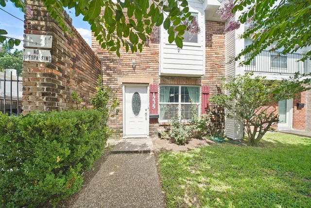 a view of a house with brick walls and a yard with plants