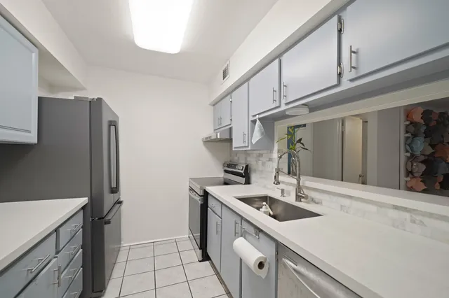 a kitchen with stainless steel appliances a sink a stove and a refrigerator with white cabinets