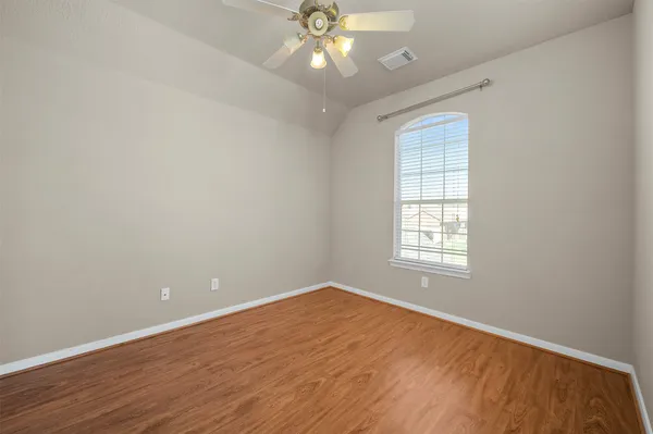 an empty room with wooden floor chandelier fan and windows