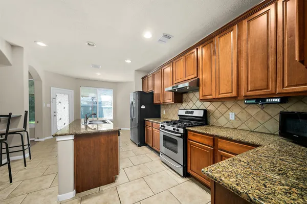 a kitchen with stainless steel appliances granite countertop a stove top oven a sink dishwasher and cabinets with wooden floor