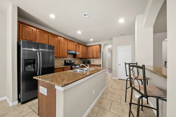 a kitchen with stainless steel appliances granite countertop table chairs refrigerator and microwave