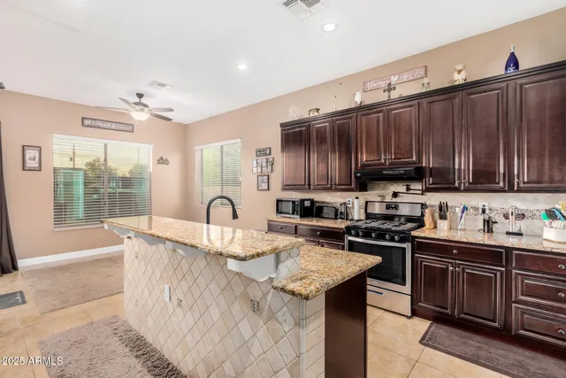 a kitchen with granite countertop a stove top oven a sink dishwasher and cabinets with wooden floor