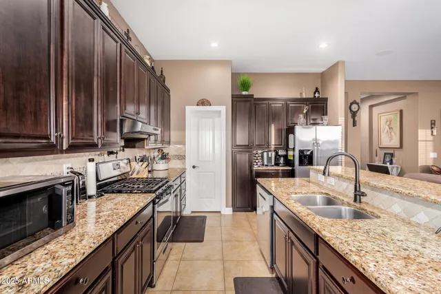 a kitchen with kitchen island granite countertop a sink counter top space appliances and cabinets