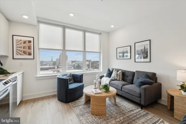 a living room with stainless steel appliances granite countertop furniture a rug a fireplace and a window