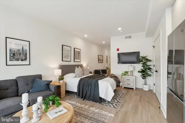 a spacious bedroom with a bed a couch and a flat screen tv