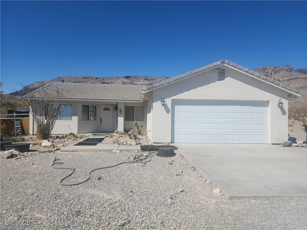 Single story home featuring a tiled roof, a mountain view, driveway, a porch, and stucco siding