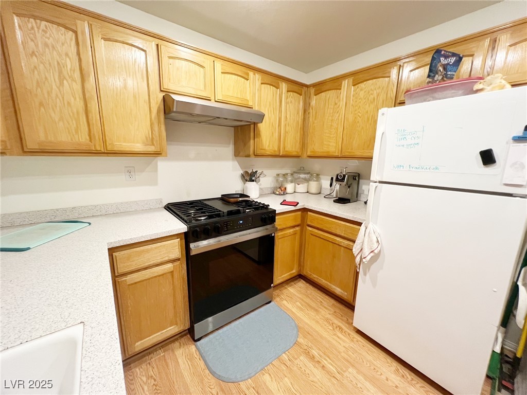 2311 West Mae Road Pahrump, NV 89060 - Photo 7 of 24 Kitchen with freestanding refrigerator, range with gas stovetop, light wood-style floors, under cabinet range hood, and light brown cabinetry