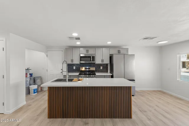 a kitchen with kitchen island granite countertop a sink a stove a refrigerator cabinets and wooden floor