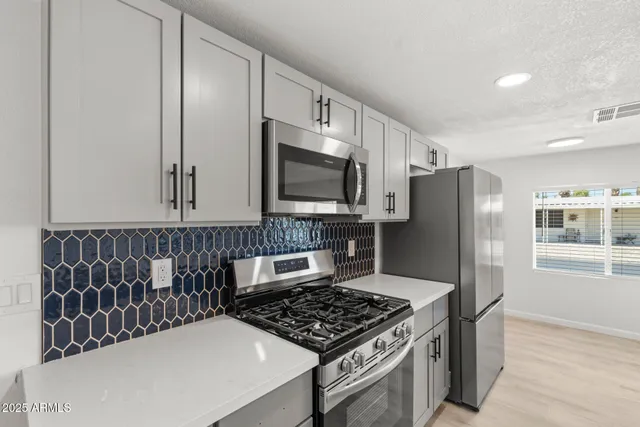 a kitchen with stainless steel appliances granite countertop a stove refrigerator and microwave
