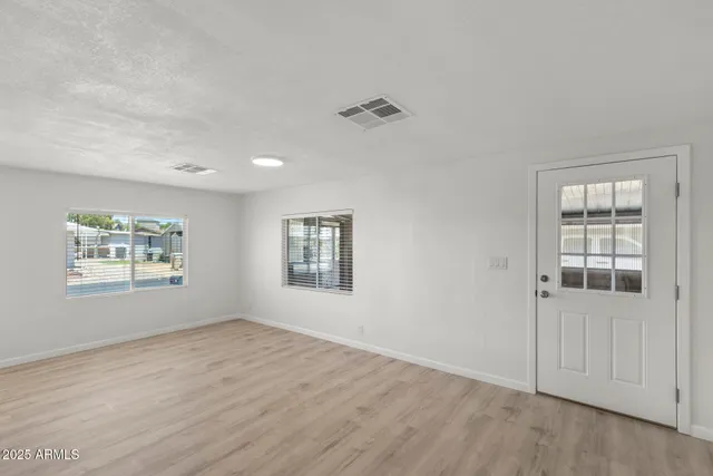 an empty room with wooden floor and windows