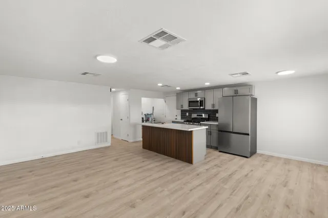 a large kitchen with stainless steel appliances kitchen island a large counter top and a stove top oven