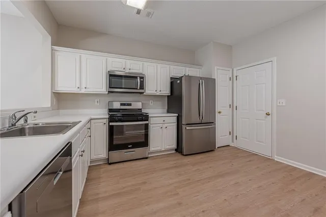 a kitchen with white cabinets stainless steel appliances and window