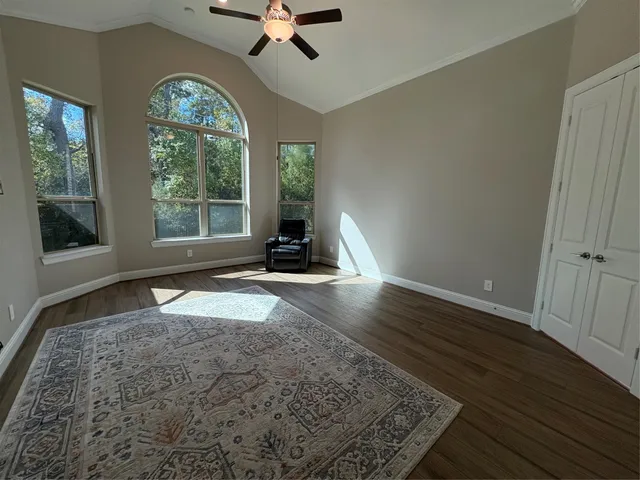 an empty room with wooden floor fan and windows