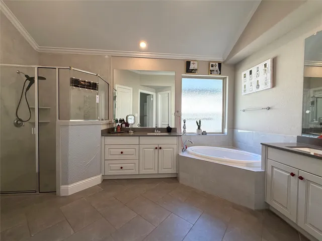 a spacious bathroom with a double vanity sink a mirror a bathtub and a shower