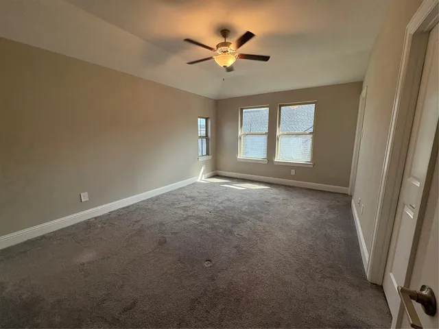 an empty room with windows and ceiling fan