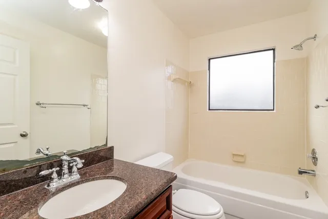 a bathroom with a granite countertop sink toilet and a bathtub