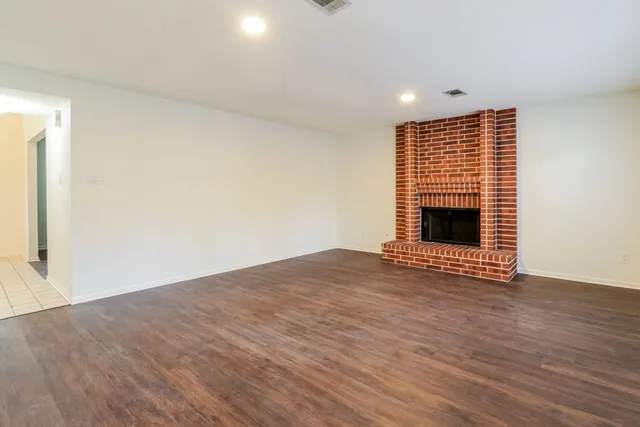 a view of empty room with wooden floor and fireplace