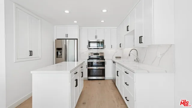 a kitchen with white cabinets and stainless steel appliances