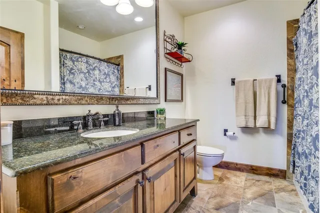 a bathroom with a granite countertop sink mirror vanity and toilet