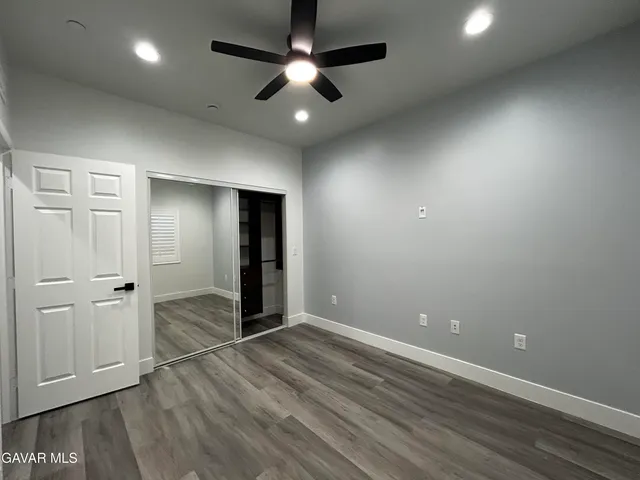 an empty room with wooden floor and ceiling fan