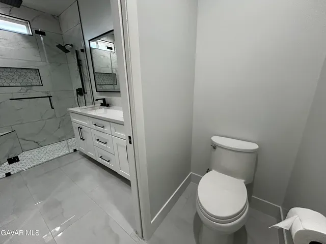 a bathroom with a granite countertop toilet and a sink