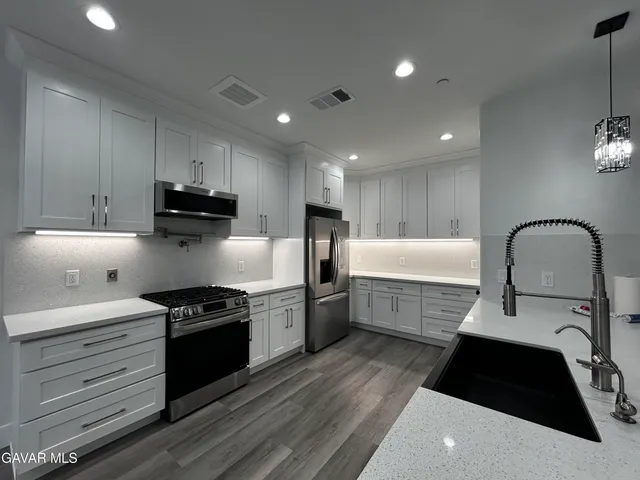 a kitchen with stainless steel appliances kitchen island granite countertop a stove a sink and a refrigerator