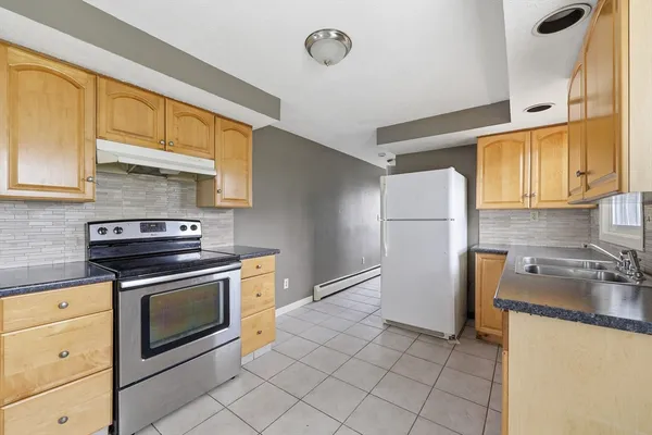 a kitchen with granite countertop stainless steel appliances a stove refrigerator and cabinets