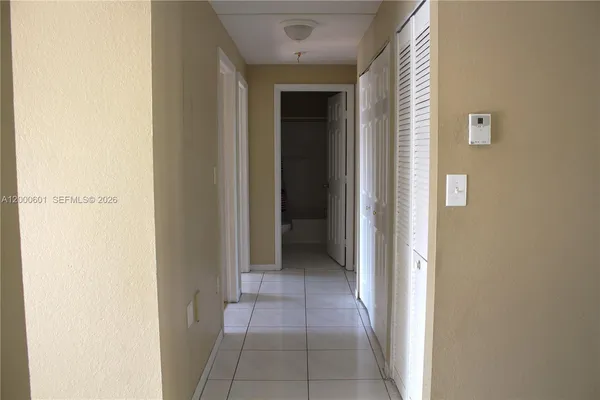 a view of a hallway with closet and a bathroom