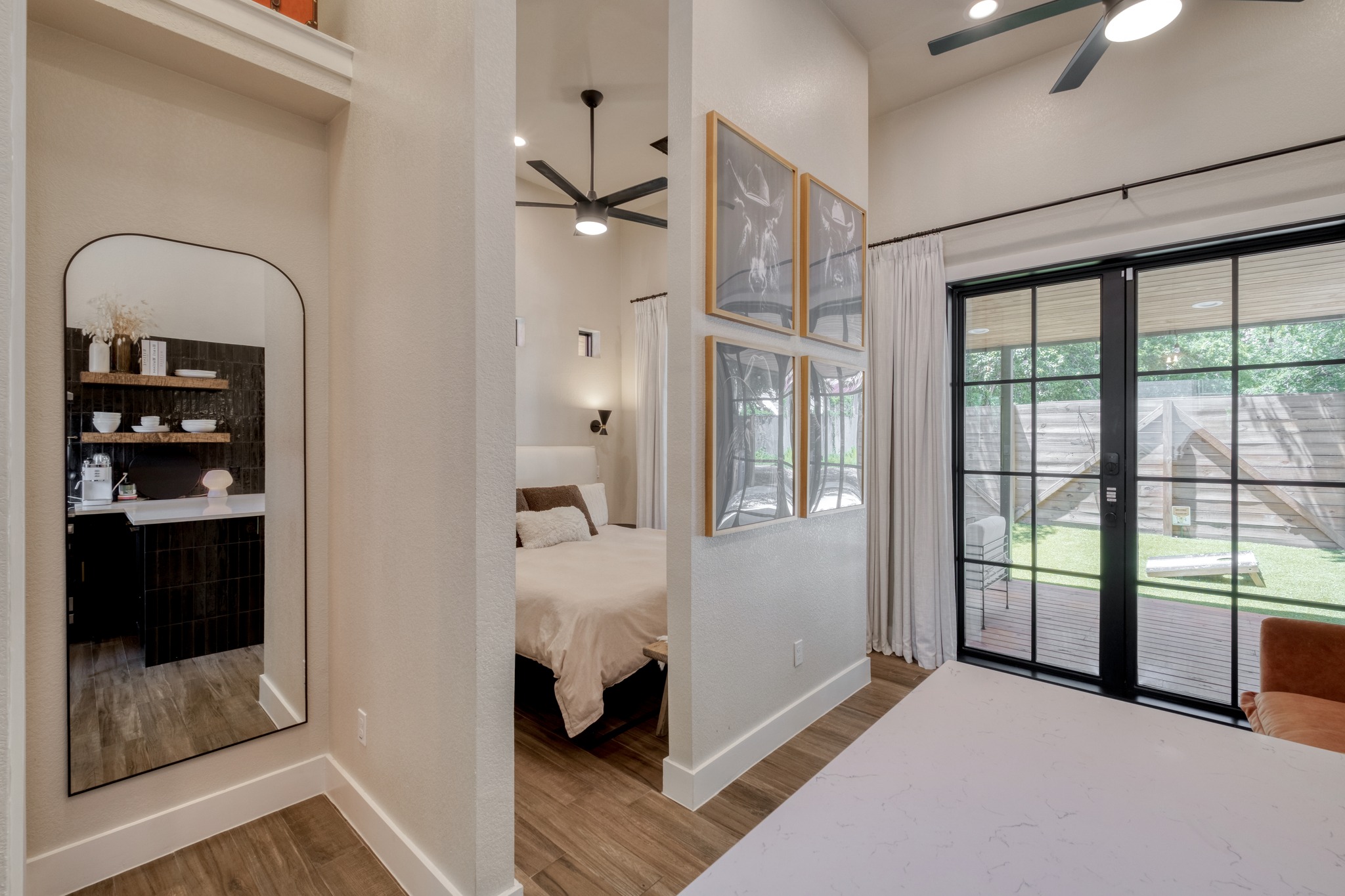 1904 East 16th Street, Unit 2 Austin, TX 78702 - Photo 12 of 20 Open-concept interior featuring wood-finish flooring, a contemporary ceiling fan, and large sliding glass doors providing access to an outdoor deck and green space
