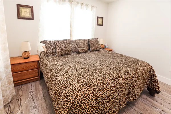 a bed sitting in a bedroom next to a window with wooden floor