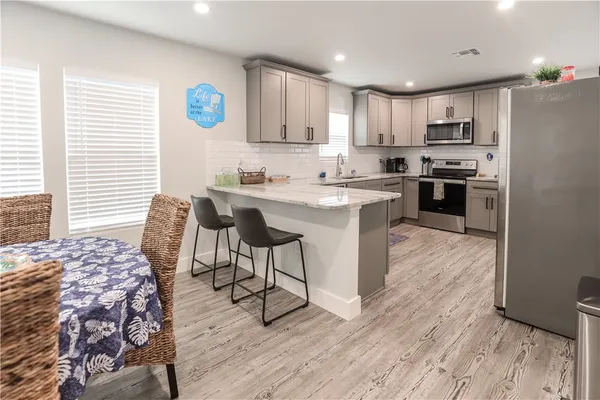 a kitchen with granite countertop a stove a sink dishwasher and a refrigerator with wooden floor