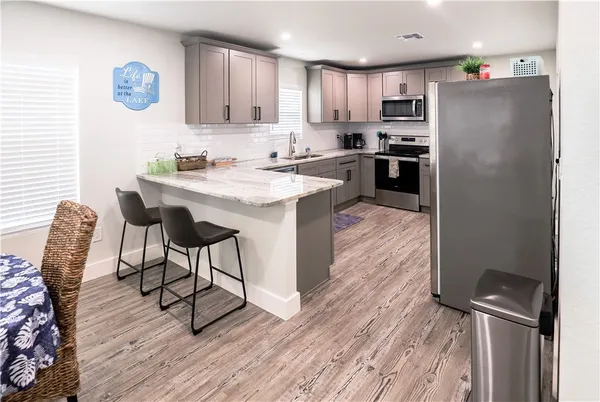 a kitchen with stainless steel appliances granite countertop a refrigerator a stove a sink dishwasher and a dining table with wooden floor