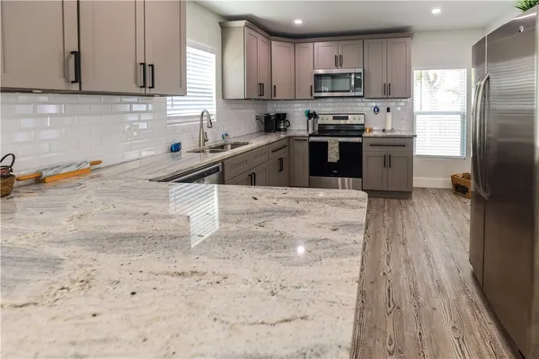 a kitchen with stainless steel appliances granite countertop a refrigerator a sink a stove and oven with wooden floor