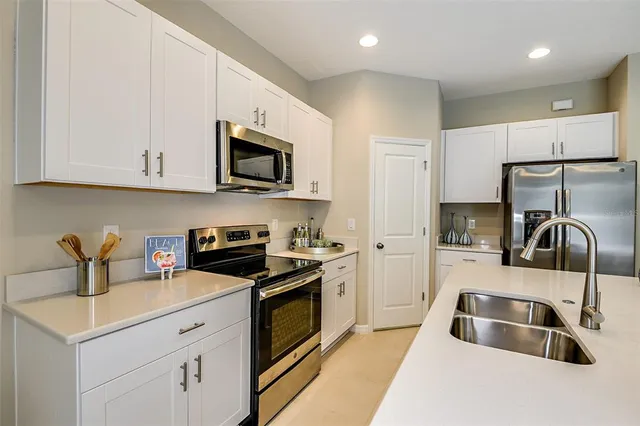 a kitchen with granite countertop a sink a stove and refrigerator