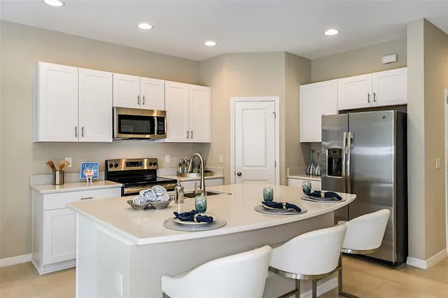 a kitchen with stainless steel appliances a sink a stove a refrigerator cabinets and a dining table