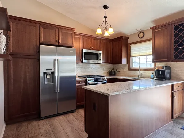a kitchen with granite countertop a refrigerator oven a sink and dishwasher wooden cabinets with wooden floor