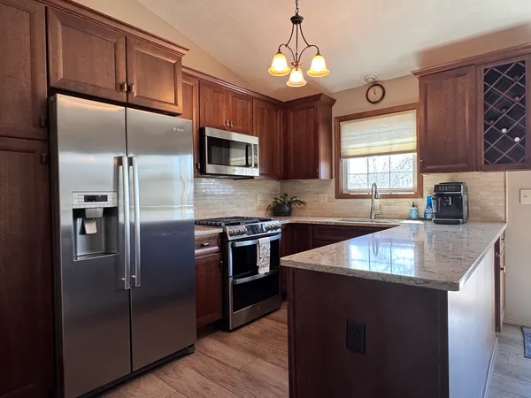 a kitchen with kitchen island granite countertop stainless steel appliances cabinets a sink and a center island