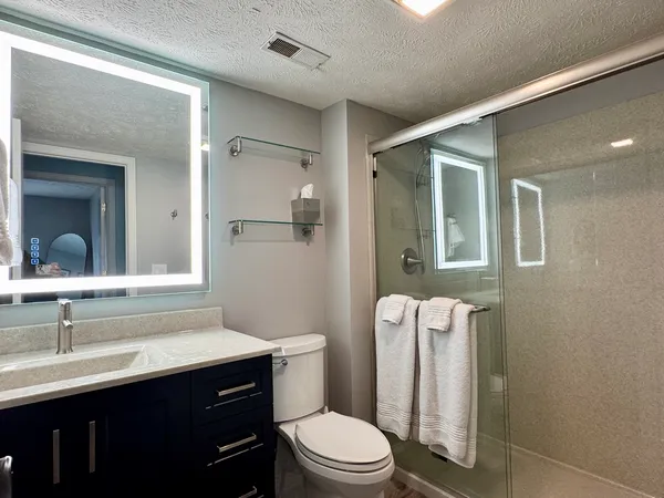 a bathroom with a sink a toilet a mirror and shower