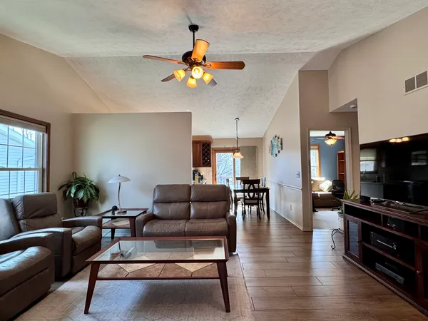 a living room with furniture a flat screen tv and kitchen view
